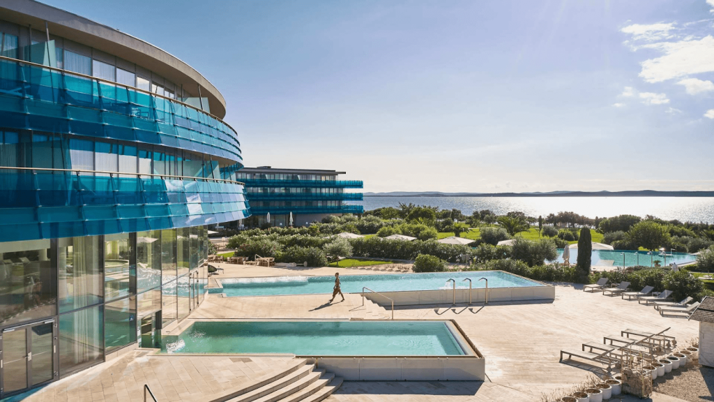 An ocean view hotel that's 3 stories and has a pool infront of it